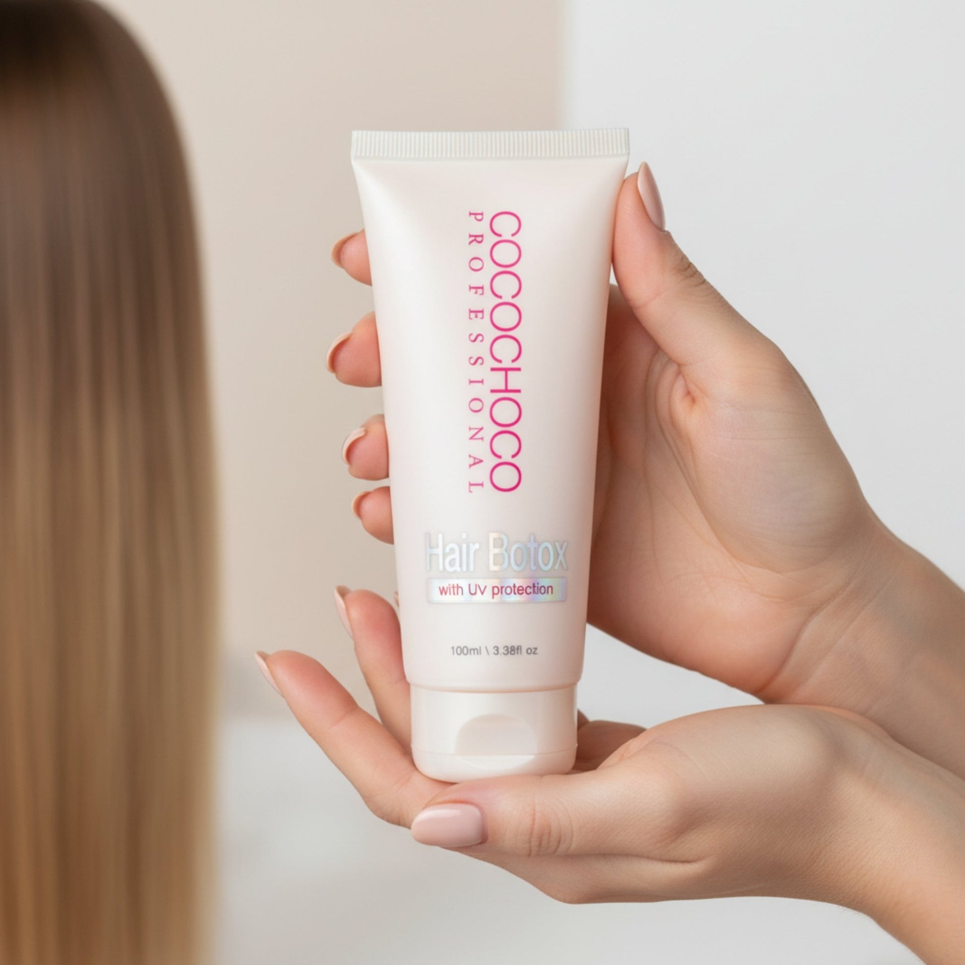 Hand holding a tube of Cocochoco hair treatment against a neutral background